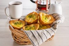 a basket filled with mini quiches sitting on top of a table next to a cup of coffee