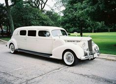 an old white car is parked on the side of the road