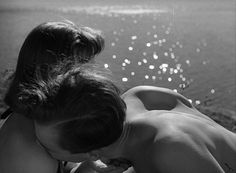 black and white photograph of two women kissing by the water with bubbles in the background