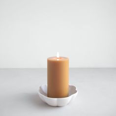 a candle sitting in a white bowl on a table