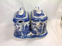 two blue and white vases sitting side by side on a white tablecloth background