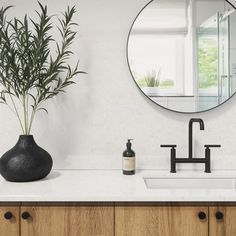 a black vase sitting on top of a white counter next to a sink and mirror