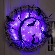 a wicker wreath decorated with halloween lights and bats is shown in front of a purple background