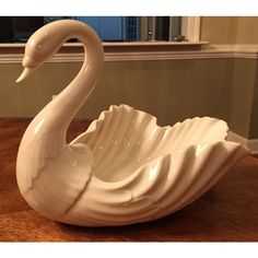 a white swan shaped bowl sitting on top of a wooden table