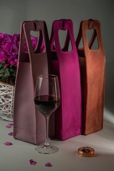 three wine bags and a glass of wine on a table