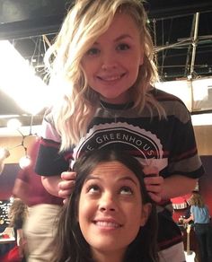 a woman is getting her hair cut by another woman who is sitting next to her