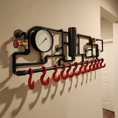 there is a clock on the wall with pipes and gauges hanging from it's side