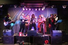 a group of people standing on top of a stage next to guitars and amps