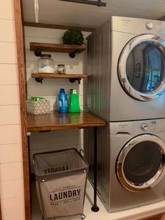 a washer and dryer in a small room with shelves on the wall above them