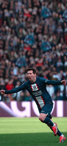 a man kicking a soccer ball on top of a field with people in the background