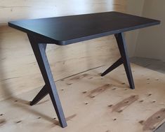 a black table sitting on top of a hard wood floor next to a white wall