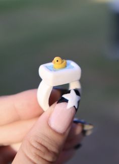 a tiny yellow rubber ducky sitting on top of a white ring with black and white stripes