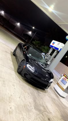 a black sports car parked at a gas station