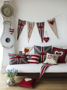 a living room filled with lots of pillows and flags hanging from the wall next to a clock