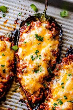 two stuffed peppers with cheese and green onions on a baking sheet, ready to be eaten