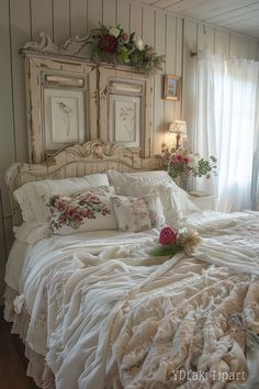 a white bed topped with lots of pillows next to a window filled with curtains and flowers