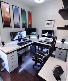 a home office with two desks and three computer screens on the wall above them