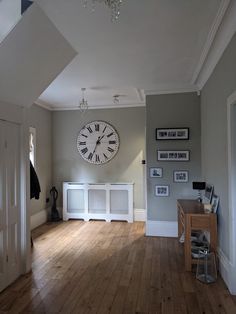 a large clock mounted to the side of a wall in a living room next to a radiator