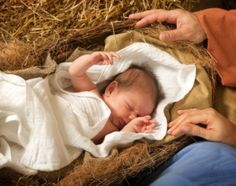 a baby is laying in the hay with his hands on it's head and an adult