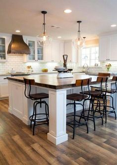 a large kitchen with an island in the middle and lots of stools around it