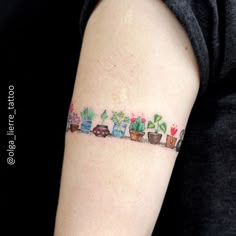 a woman's arm with a tattoo on it that has plants and cars in them