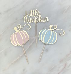 two little pumpkin cake toppers on a marble surface