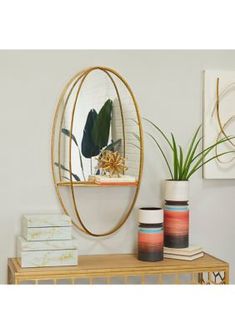 a mirror sitting on top of a wooden table next to vases and plants in front of it