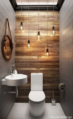 a bathroom that has some lights on the wall above the toilet and sink in it