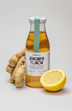 a bottle of ginger syrup next to lemons and ginger root on a white background