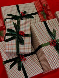 four wrapped presents with bows and holly on them