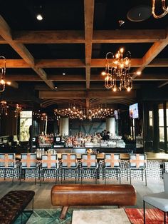 an empty bar with chandeliers hanging from the ceiling and chairs in front of it