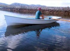 a man sitting in a white boat on top of a lake next to a stone wall