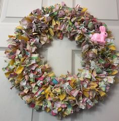 a wreath made out of folded paper with a pink toy on the front door handle