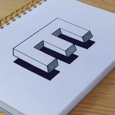 a spiral notebook with the letter e on it sitting on top of a wooden table