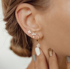 This set consists of four separate earrings, in three different styles, all made from sterling silver and embellished with zirconia stones. It has: 🌟 One stud earring with four tiny zirconia arranged in a flower shape; 🌟 One stud earring with three marquise-cut zirconia arranged in a fan shape with one small round zirconia hanging beneath; 🌟 One pair of huggie hoop earrings with a flower shaped charm hanging from their lower edge, decorated with six round zirconia. A feminine and elegant set Earrings 3 Lobes, 3 Piercings Ear Studs, Jewelry Wedding Earing Multi Holes, Flower Shaped Earrings With Diamond Accents, Flower Earrings With Diamond Accents In Cubic Zirconia, Fine Jewelry Flower Earrings, Pierced, Fine Jewelry Flower Pierced Earrings, Huggie Earrings Gold, Golden Jewelry