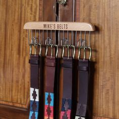 three belts hanging on a rack in front of a wooden door