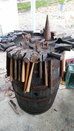 an old barrel with many tools on it and some hammers sticking out of the top