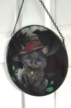 a black cat wearing a hat hanging from a chain