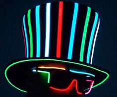 a man wearing a top hat and glasses with neon lights on his face in the dark