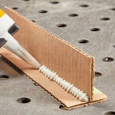 a close up of a toothbrush in a cardboard box with holes on the floor