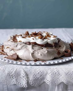 a cake with white frosting and chocolate shavings on a lace doily