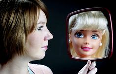 a woman is looking at herself in the mirror with her hair pulled back and blue eyes