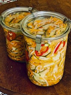 two jars filled with food sitting on top of a wooden table