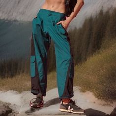 a shirtless man standing on top of a mountain with his hands in his pockets