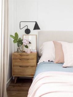 a bedroom with a bed, nightstand and plants on the night stand next to it