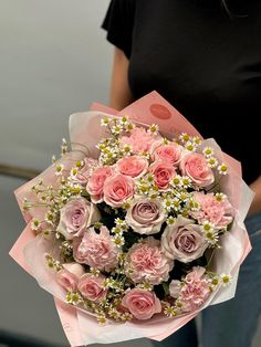 a woman holding a bouquet of pink roses