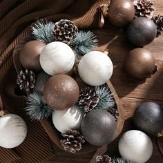 christmas ornaments are arranged on a wooden tray with pine cones and firconis in the background