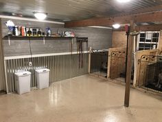 the inside of a garage with two toilets and trash cans on the floor in front of it