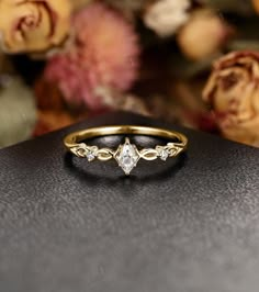 a diamond ring sitting on top of a black box next to some flowers and roses