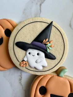 two decorated cookies sitting on top of a table next to pumpkins and jack - o'- lanterns